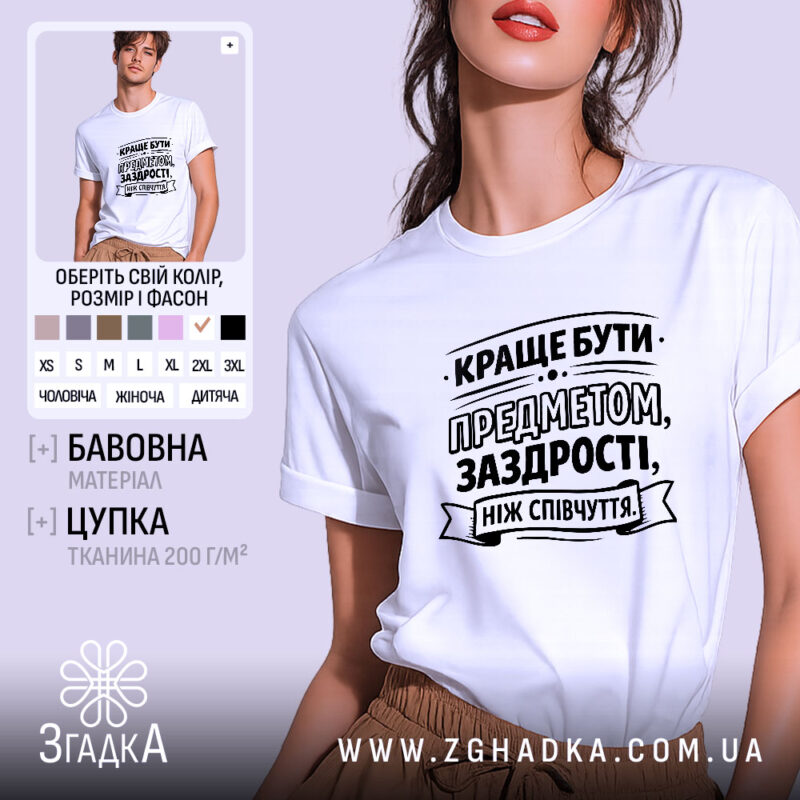 Футболка я предмет заздрості, біла, зображена на молодій людині, яка позує на світлому фоні, принт чорного кольору з текстом, що закликає бути предметом заздрості.