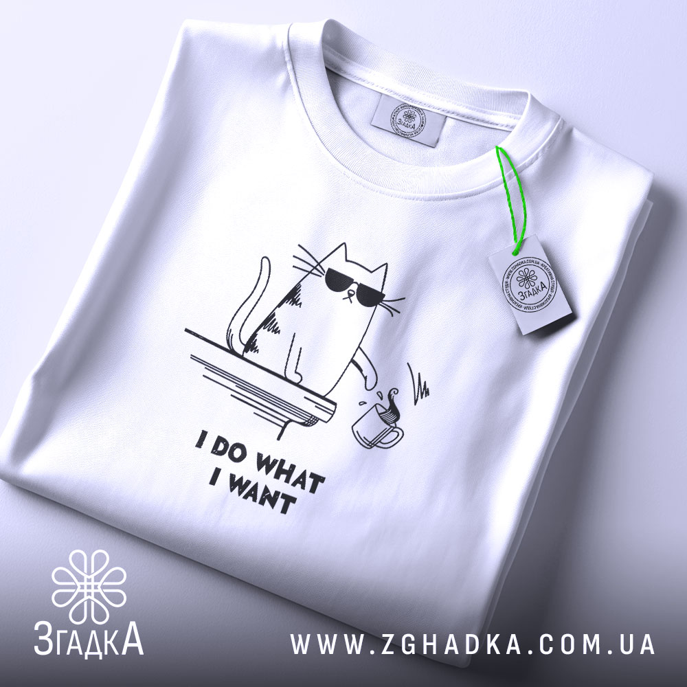 Футболка я роблю що хочу, біла, складена на поверхні, з верхнього ракурсу, фон світло-сірий, принт з котом у сонцезахисних окулярах, що тримає чашку, текст під принтом чорний.