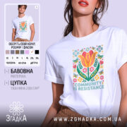 Футболка єдність і сила, біла футболка на моделі, з принтом квітів і написом 'COMMUNITY IS RESISTANCE', фон світло-фіолетовий, деталі принта яскраві, зокрема жовті і рожеві квіти.