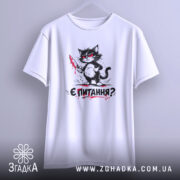 Футболка кіт є питання, біла футболка підвішена на вішалці, принт з котом з ножем, фон світлий, деталі принта чіткі і яскраві.