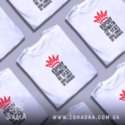 Футболка корону знімати не буду, біла футболка на молодій людині, зображена в анфас, фон світло-фіолетовий, принт червоного кольору у вигляді корони та чорного тексту.