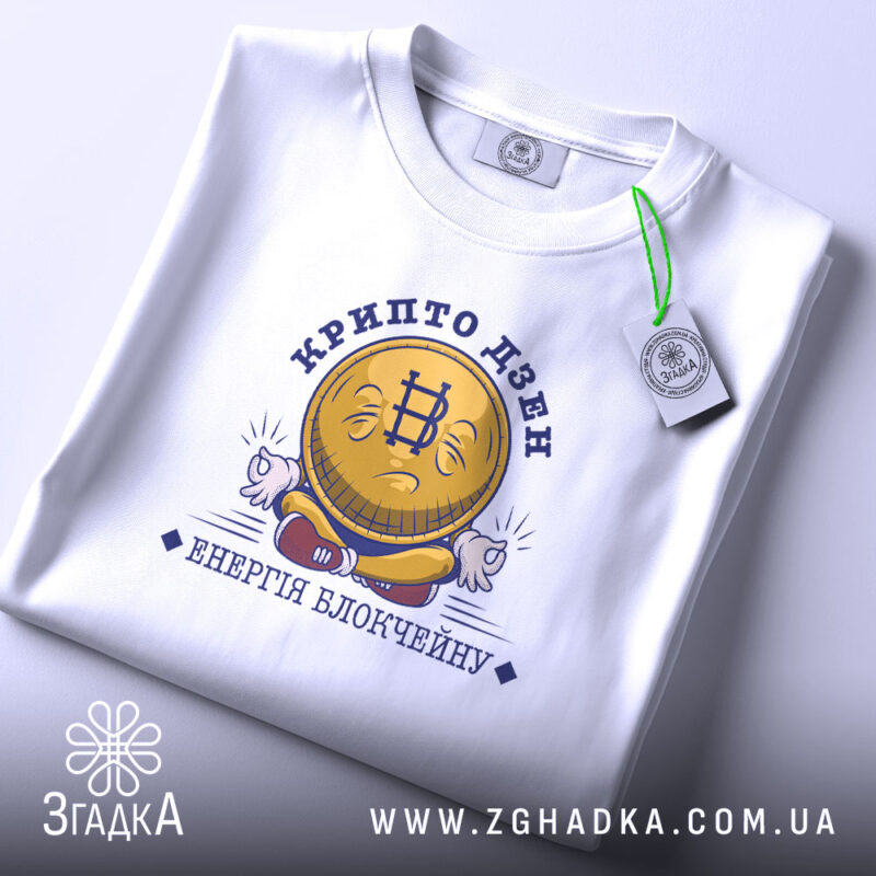 Футболка крипто дзен, біла, на плоскій поверхні, з принтом у вигляді усміхненої монети з символом біткоїна, текстом 'крипто дзен' та 'енергія блокчейну', фон світло-сірий.