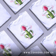 Футболка Квітка потребує зволоження. Біла футболка на моделі, з принтом червоного тюльпана, що росте з зеленого стебла. Фон світло-фіолетовий, модель позує з легким усмішкою, акцент на принті.