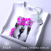 Футболка киця чекає котика. Біла футболка, зображена зверху, на фоні світло-сірого кольору. Принт з чорним котом у короні, яскравий рожевий текст, етикетка на рукаві.