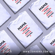 Футболка мама найкраща, біла, зображена на моделі в ракурсі спереду, фон світло-сірий, принт чорного та червоного кольору з написом 'Мама найкраща, мудра, розсудлива, добра, розумна, красива'.