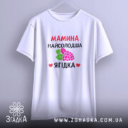 Футболка мамина найсолодша ягідка, біла, підвішена на вішалці, фон світло-сірий, принт з червоним текстом та малюнком ягід і листя.