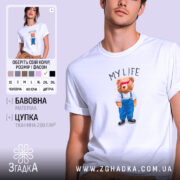 Футболка моє життя з ведмедиком, біла, на моделі, фон світло-фіолетовий, принт ведмедика в синіх штанях і білу футболку з написом 'MY LIFE'.