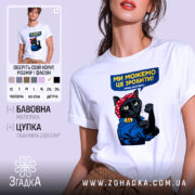 Футболка ми можемо це зробити, біла, на моделі, фон світло-сірий, принт з чорним котом у червоній бандані, що піднімає кулак, текст на футболці синій з жовтим.