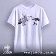 Футболка не будь як голуб. Біла футболка, підвішена на вішалці, з принтом чорного кольору, що зображує птаха з банером та дівчину, яка тримає пістолет. Фон світло-сірий, футболка має короткі рукави.