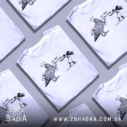 Футболка не будь як голуб. Біла футболка на чоловікові, з принтом чорного кольору, що зображує птаха з банером та дівчину, яка тримає пістолет. Фон світло-фіолетовий, футболка має круглий виріз.