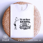 Футболка ну шо його казать, біла футболка, складена на плетеній основі, з принтом, що містить персонажа з сумним виразом обличчя та текстом "Ну шо його казать, коли воно канешно". Фон світлий, основа має текстуру.