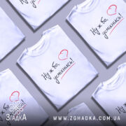 Футболка ну ж бо усміхнись, біла футболка на моделі, ракурс з правого боку, фон світло-фіолетовий, принт з написом 'Ну ж бо, усміхнись!' у чорному кольорі з червоним сердечком.