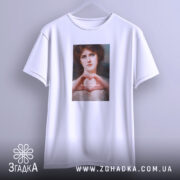 Футболка-оберіг від ідіотів, біла футболка, підвішена на вішалці, з принтом жінки, що формує серце руками, на фоні світло-сірого кольору.