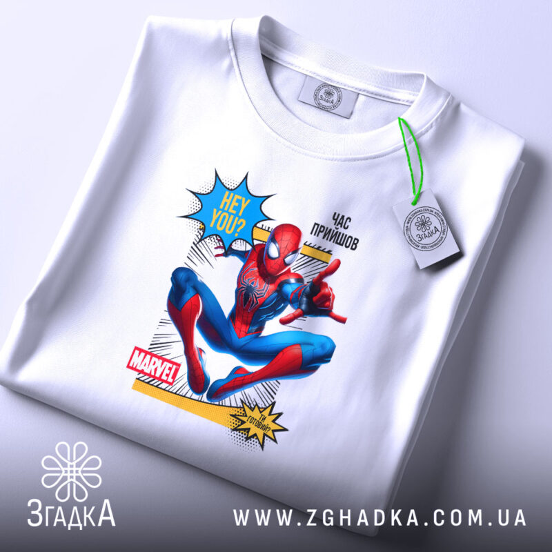Футболка павук час прийшов. Біла футболка, зображена зверху, з принтом Спайдермена. Принт яскравий, з текстом 'HEY YOU?' та 'ЧАС ПРИЙШОВ', на фоні світло-сірий колір. На футболці також видно етикетку з зеленим шнурком.