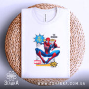 Футболка павук час прийшов. Біла футболка, розкладена на плетеній основі, з принтом Спайдермена. Принт яскравий, з текстом 'HEY YOU?' та 'ЧАС ПРИЙШОВ', фон натуральний, що створює контраст з футболкою.