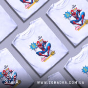 Футболка павук час прийшов. Біла футболка на молодому чоловікові, зображення спереду. Принт з персонажем Спайдермена в червоному та синьому костюмі, який сидить у динамічній позі. На фоні світло-сірий колір, що підкреслює яскравість принта.