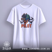 Футболка Пілот FPV білого кольору, підвішена на вішалці, з чітким зображенням принта черепа з окулярами віртуальної реальності та дронами. Принт яскравий, з червоними та чорними деталями. Фон однорідний, що акцентує увагу на футболці.