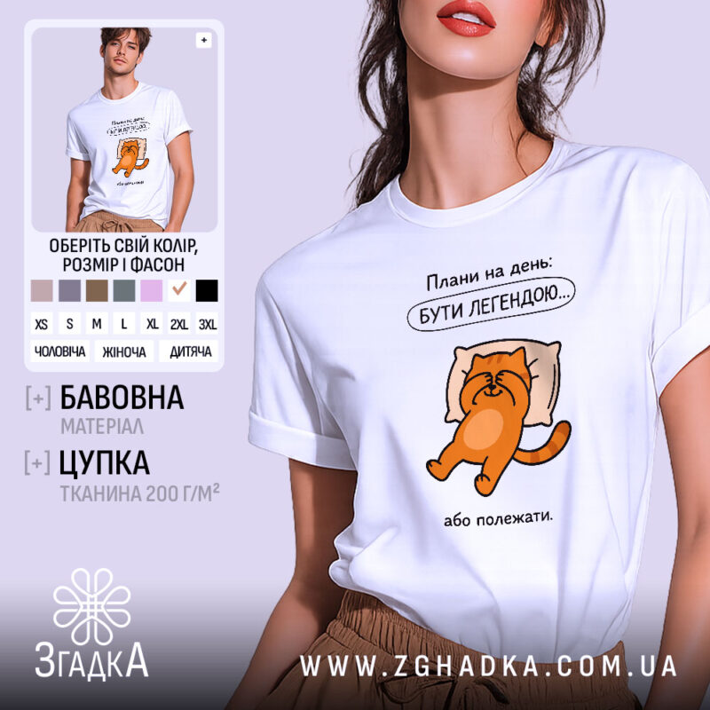 Футболка плани на день: біла футболка з коротким рукавом, зображення оранжевого кота на подушці, текст зверху "Плани на день: БУТИ ЛЕГЕНДОЮ...". Модель позує на світлому фоні, акцент на принті.