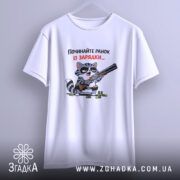 Футболка починайте ранок із зарядки. Біла футболка, підвішена на вішалці, з принтом кота з рушницею. Кот має чорні окуляри, фон світло-сірий. Текст на футболці червоний і чорний.