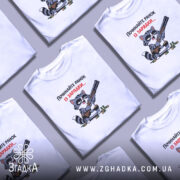 Футболка починайте ранок із зарядки. Біла футболка на моделі, з принтом, що зображує кота з рушницею. Кот має чорні окуляри та смугастий хвіст, фон світло-фіолетовий. Текст на футболці червоний і чорний.