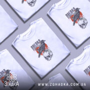 Футболка погляд вічності. Біла футболка з коротким рукавом, зображення чорного ворона, що сидить на черепі, на фоні червоного кола та графічних елементів. Модель позує на світлому фоні, з легким ракурсом зліва.