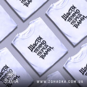 Футболка щастя прямо перед вами, біла, з коротким рукавом, зображена на моделі, фон світло-фіолетовий, принт чорний з написом 'Щастя прямо перед вами' у стилі графіті.