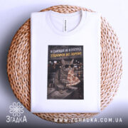 Футболка сьогодні не в ресурсі. Біла футболка, зображення кота в окулярах з шматком піци, розташоване на футболці, яка лежить на плетеній основі. Текст на принті жовтого кольору зверху: 'Я сьогодні не в ресурсі'.