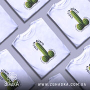 Футболка Стоїть довго, біла, на моделі, з принтом у вигляді кактусів, фон світло-фіолетовий, текст над принтом чорний, напис 'СТОЇТЬ ДОВГО' розташований зверху.