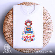 Футболка танці до ранку, біла, складена на плетеній основі, фон білий, принт з дівчиною в національному вбранні з навушниками, яскраві кольори принта, текст 'Танці до ранку' внизу.