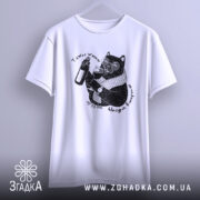 Футболка тяжко жити шкода вмерти, біла, підвішена на вішалці, ракурс спереду, фон світло-сірий, принт з чорним котом у окулярах, що тримає пляшку та келих, текст навколо принта.