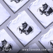 Футболка тяжко жити шкода вмерти, біла, зображена на чоловікові, ракурс спереду, фон світло-фіолетовий, принт з чорним котом у окулярах, що тримає пляшку та келих, текст навколо принта.