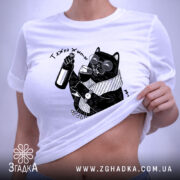 Футболка тяжко жити шкода вмерти, біла, складена на поверхні, ракурс зверху, фон світло-сірий, принт з чорним котом у окулярах, що тримає пляшку та келих, з етикеткою на рукаві.