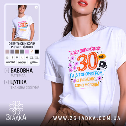 Футболка тобі 30 років. Біла футболка на моделі, з принтом на грудях, що містить яскраві кольори: оранжевий, рожевий, блакитний та чорний. Фон світло-фіолетовий, модель позує в три чверті, демонструючи деталі принта, що включає текст і малюнки квітів.