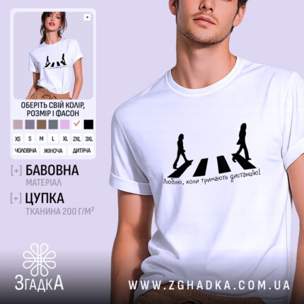 Футболка тримайте дистанцію, біла, на моделі з чоловічим обличчям, фон нейтральний, принт з двома силуетами людей, які йдуть по пішохідному переходу, текст під ними: 'Люблю, коли тримають дистанцію!'
