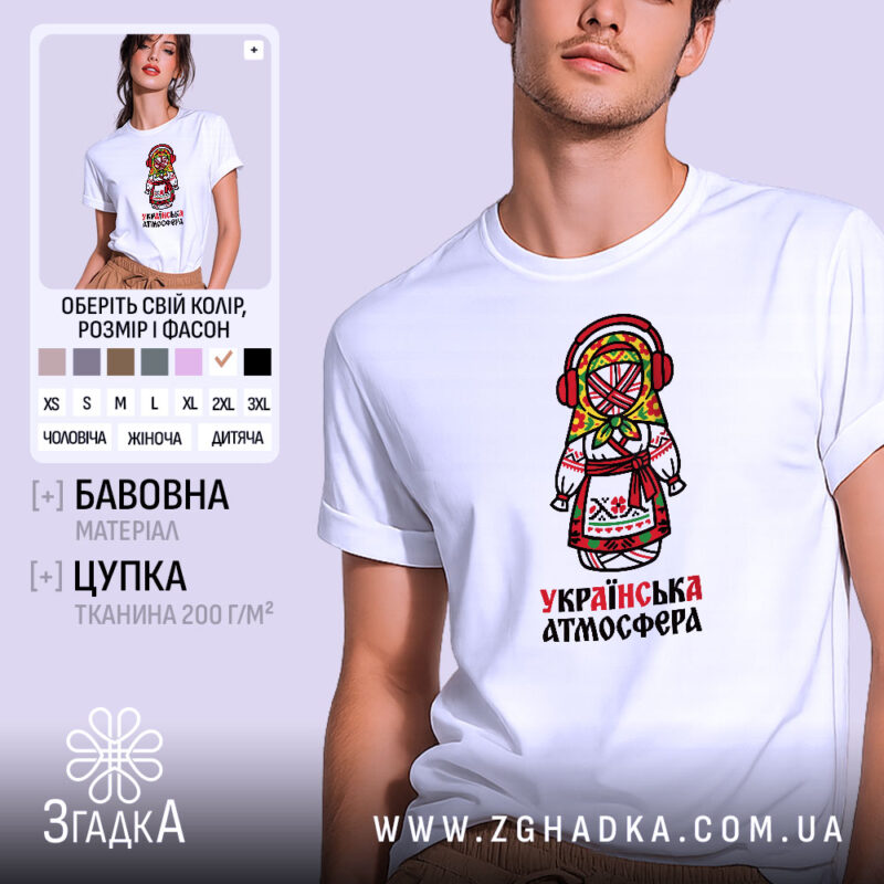 Футболка українська атмосфера, біла, на моделі, з принтом у вигляді ляльки-мотанки в традиційному вбранні, фон світло-фіолетовий, деталі принта яскраві, з червоними навушниками та кольоровим головним убором.