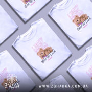 Футболка ведмедик і удача, біла, зображена на моделі, фон світло-фіолетовий, принт з ведмедиком у сонцезахисних окулярах та написами 'Lucky You' і 'Best of Luck'.