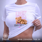 Футболка ведмедик і удача, біла, зображена на плоскій поверхні, фон світлий, принт з ведмедиком у сонцезахисних окулярах та написами 'Lucky You' і 'Best of Luck', видна етикетка.
