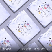 Футболка Весна Літо Осінь Зима, біла футболка на моделі, з принтом, що містить квіти та метеликів, ракурс зліва, фон світло-фіолетовий, деталі принта включають слова 'Spring', 'Summer', 'Fall', 'Winter' та 'Love for all seasons'.