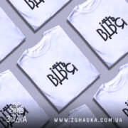 Футболка від'їбіться, біла футболка на моделі, ракурс зліва, фон світло-фіолетовий, принт чорного кольору з написом 'ВІДЬМ' у стилізованому шрифті.