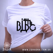 Футболка від'їбіться, складена біла футболка на світлому фоні, ракурс зверху, принт чорного кольору з написом 'ВІДЬМ', на футболці є етикетка з зеленим шнурком.