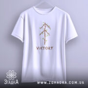Футболка VIKTORY білого кольору, підвішена на вішалці, з принтом у вигляді дерева з коричневими гілками та зеленим листям, розташованим по центру. Фон світло-фіолетовий, що підкреслює футболку.