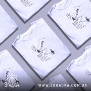 Футболка Володимир Сосюра з автографом, біла, на моделі, з легким ракурсом спереду, фон світло-фіолетовий, принт з зображенням автора та гірського пейзажу, текст під малюнком.