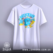 Футболка випускник молодшої школи, білого кольору, підвішена на вішалці. На фоні ніжно-фіолетовий колір. Принт яскравий, з малюнками дітей та книжок, а також написом 'ВИПУСКНИК 4-А клас', виконаний у синіх та жовтих кольорах.