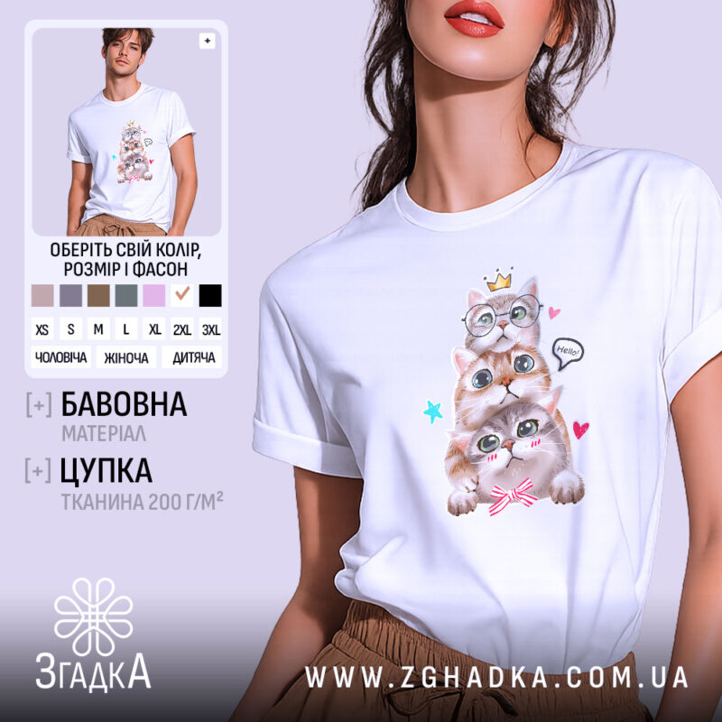 Футболка з котиками білого кольору, зображена на моделі з коротким рукавом, фон світло-фіолетовий, принт з трьома котиками, один з них у окулярах, з короною на голові, з написом 'Hello' та сердечками.