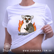 Футболка зазбогійся з лемуром, біла, знята зверху, фон світло-сірий, принт з лемуром з червоними очима та вогнем, етикетка на рукаві.