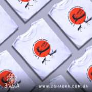 Футболка журавлі та мрія, біла футболка на моделі, зображена з близького ракурсу, фон світло-сірий, принт містить червоне сонце та журавлів, текст на футболці українською мовою.