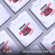 Футболка жигастайл білого кольору, зображена на молодій людині, що позує в анфас. На фоні світло-сірий колір, принт з червоним автомобілем та написом 'Жигастайл' виконаний у червоному кольорі. Додаткові деталі принта включають сірі хмари та гаражні ворота.