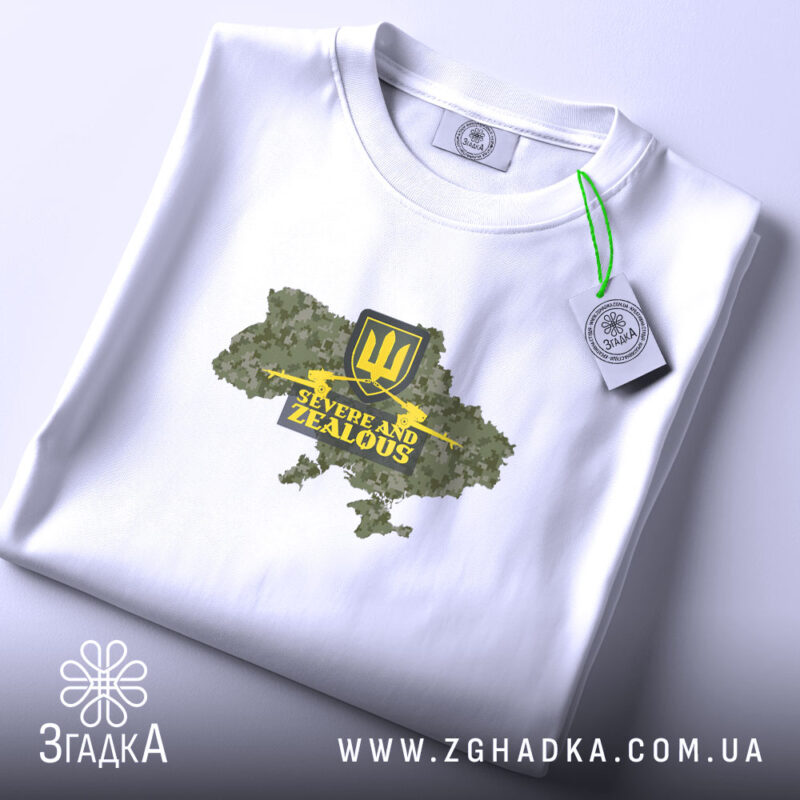 Футболка ЗСУ стиль, складена біла футболка з принтом у вигляді карти України, жовтий герб тризуба та напис 'Severe and Zealous', фон світлий, футболка лежить на поверхні.