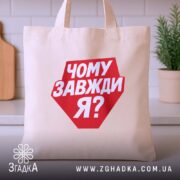 Шопер чому завжди я, бежевий, на кухонному фоні, з червоним принтом, бренд.