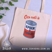 Шопер ось тобі й крінж у томаті, бежевий, на фоні рослин, бренд.